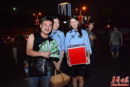 从湘潭赶来看焰火的土豪哥一次性买了10包义卖槟榔，他兴奋地和义卖的同学合影。 李毅 摄