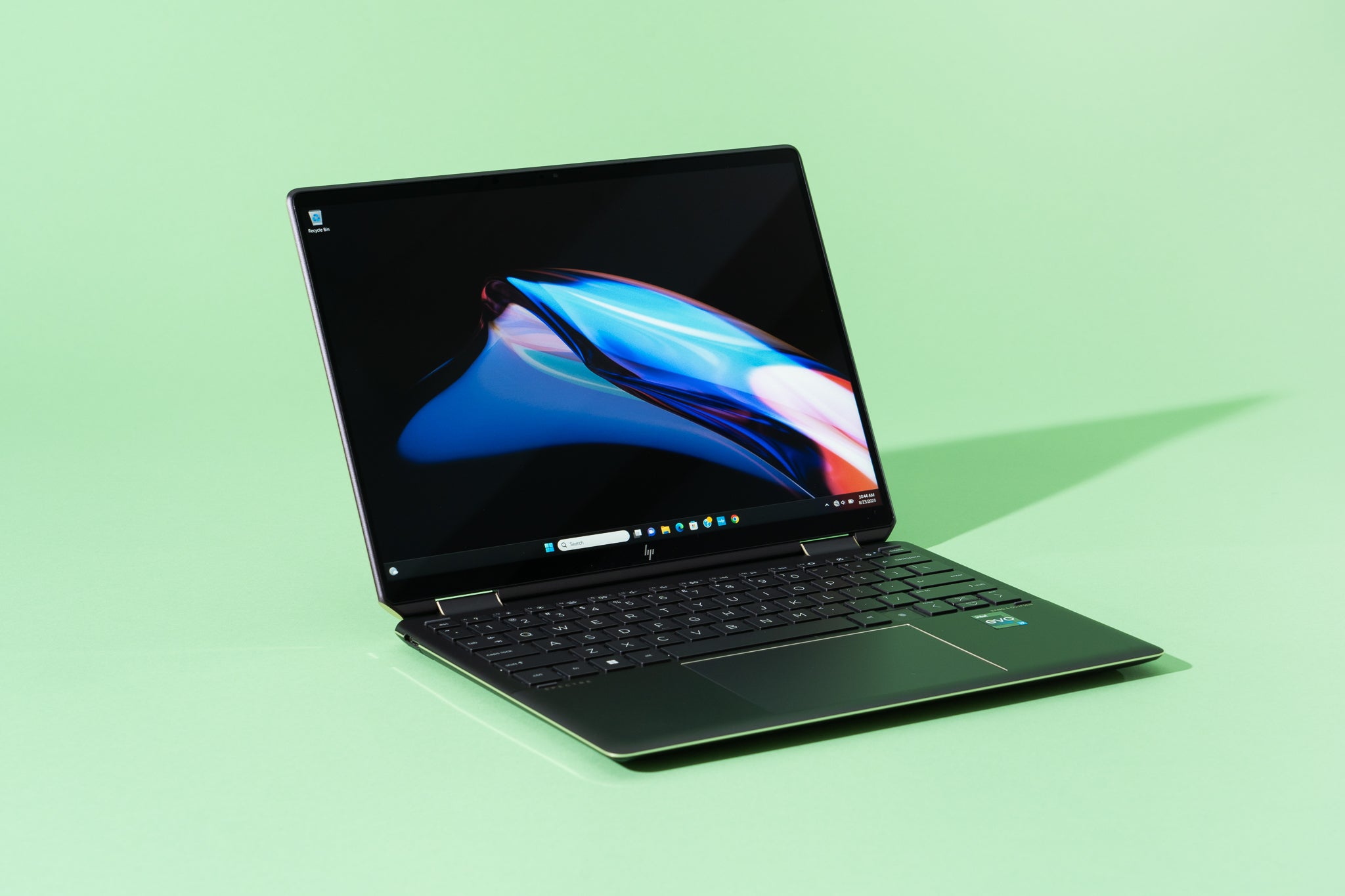HP Spectre x360显示一个抽象的主屏幕，靠在绿色背景上。